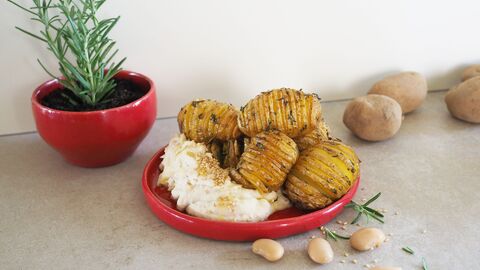 Kräuter-Fächerkartoffeln auf einem roten Teller mit einem weißen Bohnen-Dip