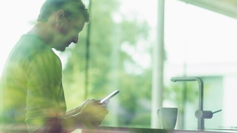 Ein Mann liest auf dem Handy in einer Küche