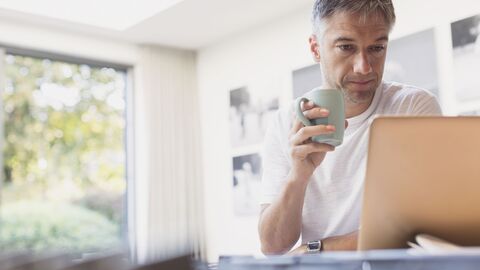 Anmeldung Fachverteiler Mann vor einem Notebook mit Kaffeetasse