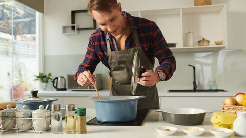 Impressum  Ein Mann kocht und schaut in einen Topf