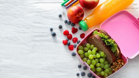 Butterbrotdose, Schreibstifte und eine Saftflasche auf einem Tisch